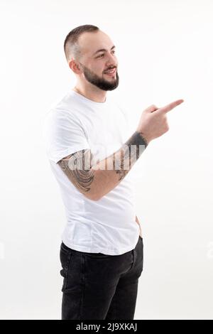 Un uomo sorridente e eccitato in verticale con un look da baffi in un abito casual. Puntando, presentando un certo prdotto Foto Stock