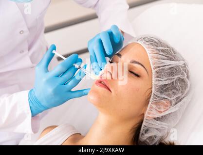 Donna che ottiene le iniezioni di contorno del viso Foto Stock