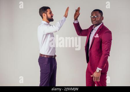 Due uomini di affari fiduciosi che parlano alto cinque lavoro di squadra azienda internazionale buon affare.afro americano ed europeo uomo in studio su sfondo bianco Foto Stock