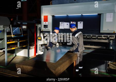 Operatori tecnici che lavorano con lamiera su pressa idraulica CNC. Foto Stock