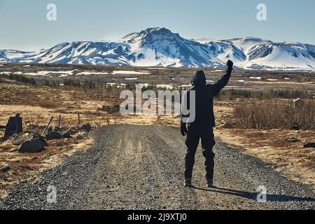 Uomo che cammina su strada di ghiaia in Islanda Foto Stock