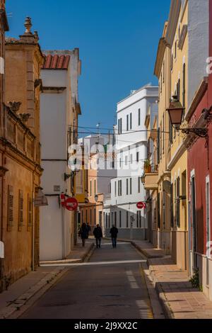 Vista della coppia camminando lungo la strada color pastello nel centro storico, Ciutadella, Minorca, Isole Baleari, Spagna, Europa Foto Stock