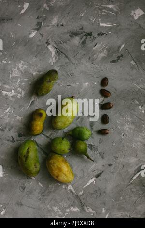 Frutta fresca della zampa disposta su un fondo grigio testurizzato Foto Stock