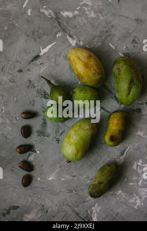 Frutta fresca della zampa disposta su un fondo grigio testurizzato Foto Stock