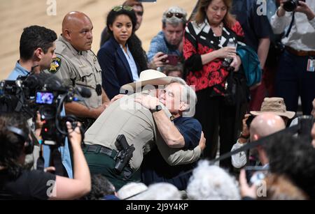 Uvalde, Stati Uniti. 25th maggio 2022. Il governatore del Texas GREG ABBOTT abbraccia un ufficiale di polizia in un servizio di guarigione a livello comunitario presso la zona fieristica della contea di Uvalde. L'evento segue un'azione di massa alla Robb Elementary School di Uvalde, dove martedì un cannoniere uccise 19 studenti e due insegnanti. Credit: Bob Daemmrich/Alamy Live News Foto Stock