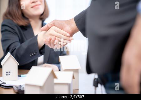 Suggellando un concetto di trattativa, l'agente immobiliare agita le mani con il cliente dopo la firma del contratto. Foto Stock
