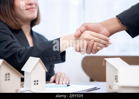 Suggellando un concetto di trattativa, l'agente immobiliare agita le mani con il cliente dopo la firma del contratto. Foto Stock