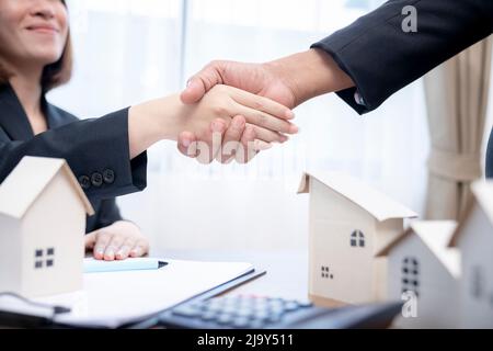 Suggellando un concetto di trattativa, l'agente immobiliare agita le mani con il cliente dopo la firma del contratto. Foto Stock