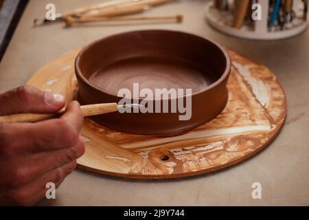 primo piano le mani sporche di un uomo donna vasaio, creando un vaso di terra argilla sul cerchio ruota del vasaio in studio copyspace officina Foto Stock