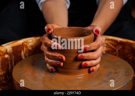 Bella donna del padrone del vasaio forgia da vaso di creta in mastre. Scultore dello studente femminile lavora con creta sulla ruota di un Potter ed al tavolo con il Foto Stock