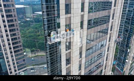 Alto e professionale servizio di pulizia delle finestre in gondola. Due lavoratori utilizzano attrezzature specializzate per accedere e pulire finestre di grattacielo come Foto Stock