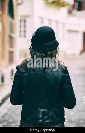 Vista posteriore della donna che indossa giacca in pelle per strada Foto Stock