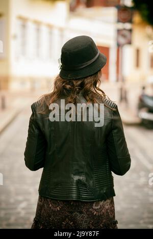 Vista posteriore della donna che indossa giacca in pelle per strada Foto Stock