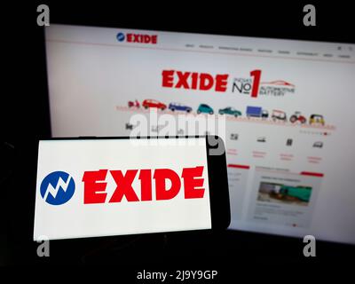 Persona che tiene lo smartphone con il logo della società indiana Exide Industries Ltd. Di batterie sullo schermo di fronte al sito Web. Mettere a fuoco sul display del telefono. Foto Stock