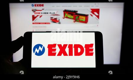 Persona che tiene il telefono cellulare con il logo della società indiana di batterie Exide Industries Ltd. Sullo schermo di fronte alla pagina web. Mettere a fuoco sul display del telefono. Foto Stock