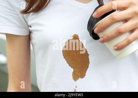 Macchia di caffè. Ragazza irriconoscibile che spillava caffè caldo su se stessa. Il concetto di pulizia delle macchie sui vestiti Foto Stock