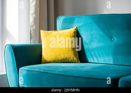 Cuscino giallo brillante su blu, divano o divano turchese, interno della confortevole camera residenziale Foto Stock