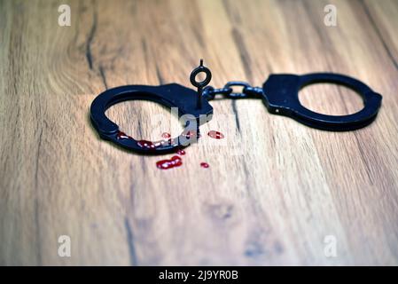 manette in metallo nero con sangue Foto Stock