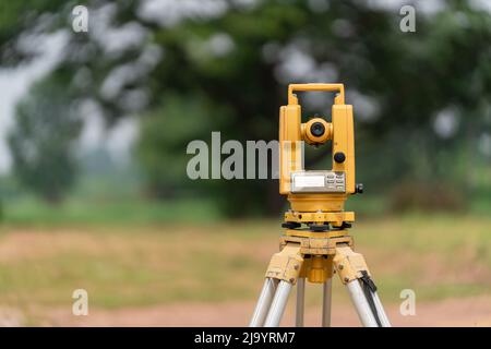 Retro dell'attrezzatura Surveyors (teodolite o stazione di posizionamento totale) sul cantiere della strada o dell'edificio con macchinari per l'edilizia bac Foto Stock