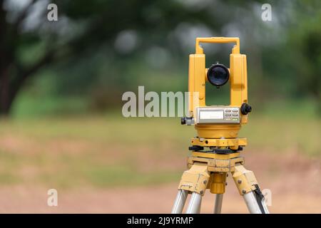 Fronte delle apparecchiature Surveyors (teodolite o stazione di posizionamento totale) sul cantiere della strada o dell'edificio con macchine da costruzione ba Foto Stock