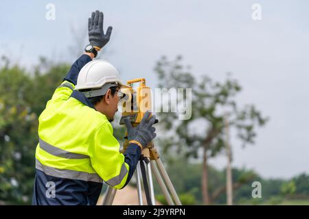 Asian Surveyor Civil Engineer che lavora teodolite o stazione di posizionamento totale sul cantiere. Foto Stock