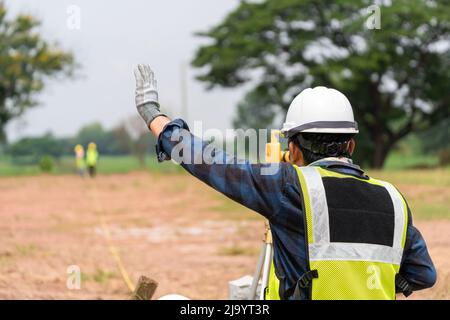 Surveyor costruttore civile Ingegnere con apparecchiature di transito teodolite al piano di costruzione. Foto Stock