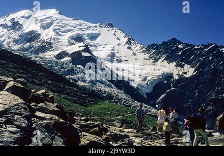 Aiguille de Bionnassay con campi di abete, Glacier de Bionnassay del Nid d'Aigle. Turisti in primo piano. Saint-Gervais-les-Bains, Francia, 1990 Foto Stock