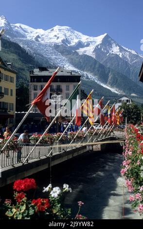 Al fiume Arve vista della bandiera e fiori strada decorata, con il massiccio del Monte Bianco alle spalle, Chamonix-Mont-Blanc, Haute-Savoie, Francia, luglio 1990 Foto Stock