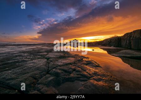 Alba invernale sopra il Castello di Bambburgh, Northumberland, Inghilterra, Regno Unito Foto Stock