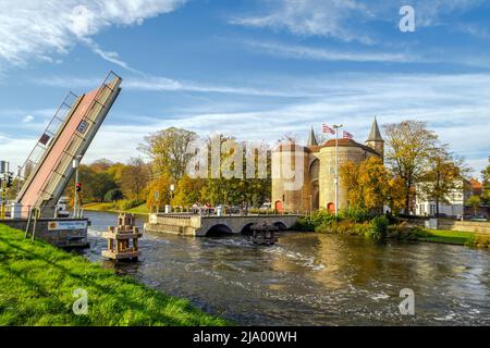 Bruges, Belgio - 12 novembre 2021: - La porta Gentpoort o Ghent, una parte del 15th secolo delle difese della città. Aprire il ponte levatoio e le persone in attesa Foto Stock