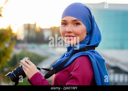 Donna fotografa che indossa un hijab. Donna che tiene una macchina fotografica hobbyist o un giornalista in estate parco alberi autunno foresta Foto Stock