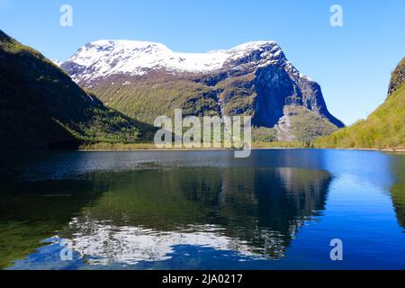 Vista sul lago Lovatnet da Kjenndalstova, Norvegia. Cime di montagna innevate e acqua blu limpida. Foto Stock