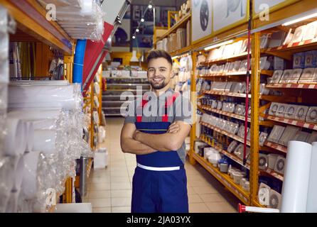 Ritratto di felice sorridente assistente di vendita in piedi in una delle corsie al negozio di hardware Foto Stock