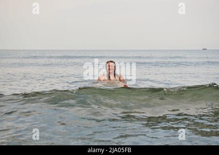 un uomo con capelli lunghi bagna nel mare Foto Stock