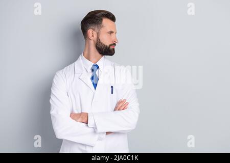 Ritratto di attraente esperto contenuto medico regista braccia piegate guardando da parte spazio copia isolato su sfondo grigio pastello colore Foto Stock