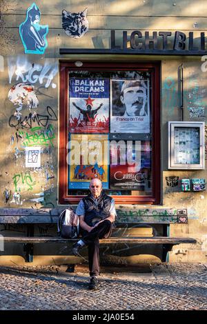 Uomo anziano seduto su panchina fuori dal vecchio cinema storico di Lichtblick a Kastanienalle, Prenzlauerberg, Berlino Foto Stock