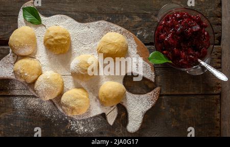 Impasto per polpettine con confettura di ciliegie su tavola di legno, su tavola con farina Foto Stock