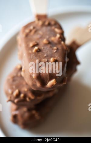 Tre gelato alla vaniglia di mandorle su un bastone con glassa al cioccolato. Foto Stock