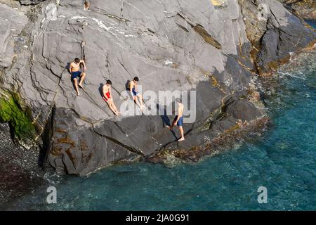 Vista su una scogliera della passeggiata di Nervi con un piccolo gruppo di adolescenti (circa 16-17 anni) che prendono il sole sulla riva, Genova, Liguria, Italia Foto Stock