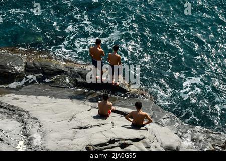 Vista su una scogliera della passeggiata di Nervi con un piccolo gruppo di adolescenti (circa 16-17 anni) che prendono il sole sulla riva, Genova, Liguria, Italia Foto Stock