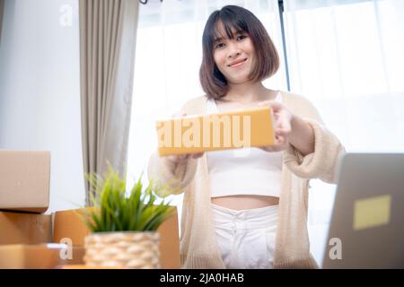 Sorridente commerciante femmina che prepara una scatola del pacchetto per trasportare ai clienti nel paese. Foto Stock