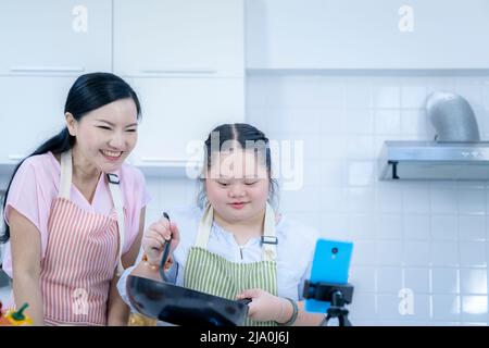 Persona asiatica con sindrome di Down che cucinano con la mamma. Crescita del cervello imparare famiglia amore intelligenza cottura Foto Stock