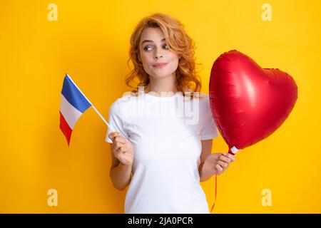 Istruzione e apprendimento in Francia. Divertente donna che tiene bandiera della Francia e palloncino rosso cuore. Foto Stock
