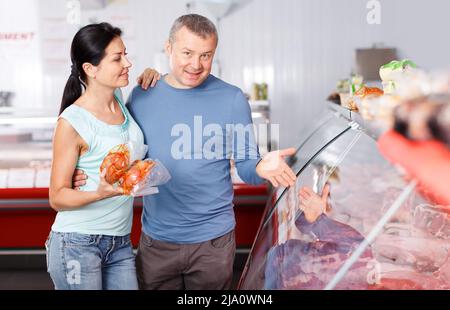 I clienti positivi della coppia scelgono la carne nel negozio Foto Stock