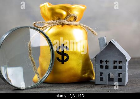 Lente d'ingrandimento, Money bag e casa. Comprando un concetto della casa Foto Stock