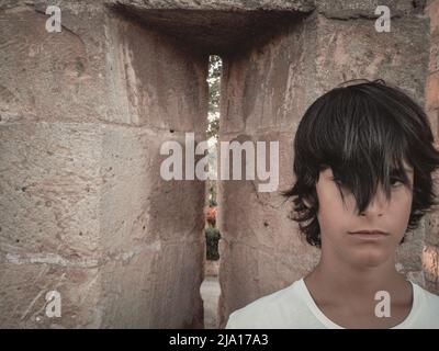 Primo piano ritratto di un bel ragazzo con una frangia che gli copre gli occhi Foto Stock