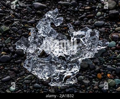 Blocco di ghiaccio sulla spiaggia nera di fronte alla laguna di Jökulsarlón, Islanda Foto Stock