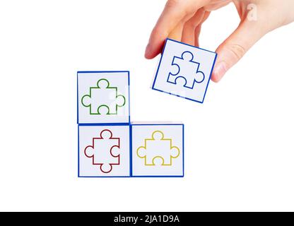 Mettere a mano cubi con pezzi puzzle colorati insieme isolato su sfondo bianco. Trovare una soluzione da una situazione difficile, un problema logico, un concetto di strategia. Foto di alta qualità Foto Stock