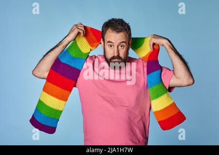 ritratto uomo gay con sciarpa color arcobaleno. Gay PRIDE Day. Comunità lgbq. Foto Stock