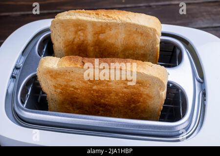 Dal tostapane fuoriescono fette di pane tostato. Cibi sani per la colazione e tecnologia di riscaldamento. Foto Stock